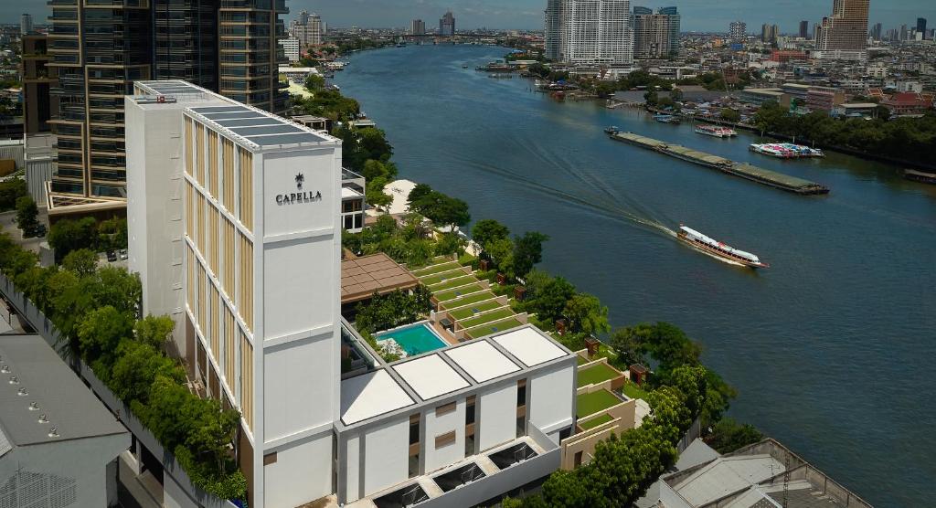 A guest relaxing on a private balcony overlooking the Chao Phraya River at Capella Bangkok.