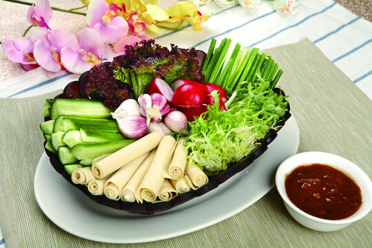 A platter of Nam Phrik Num and Nam Phrik Ong served with fresh vegetables and crispy pork rinds.