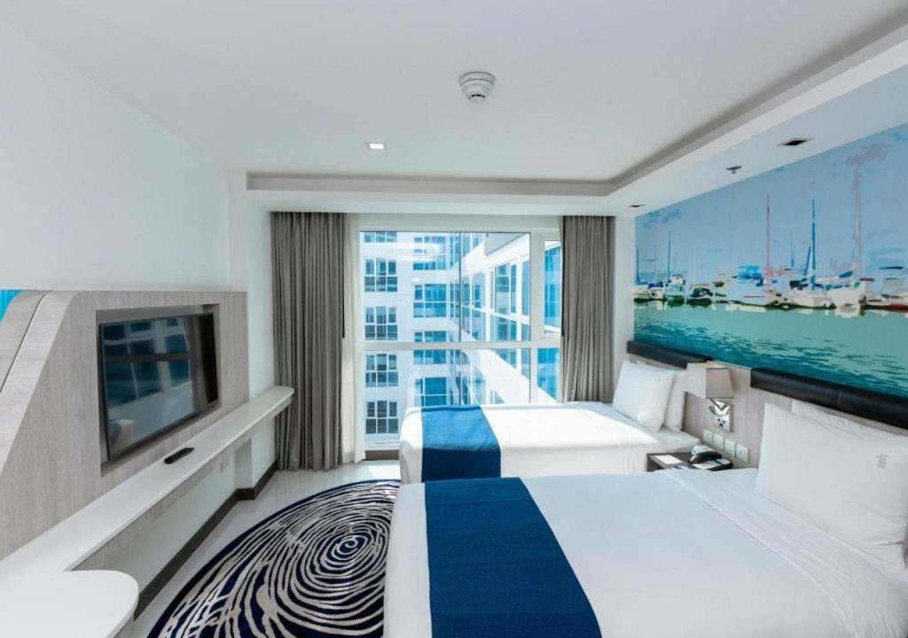 The modern facade of the Holiday Inn Express Pattaya Central, showcasing its inviting rooftop swimming pool.