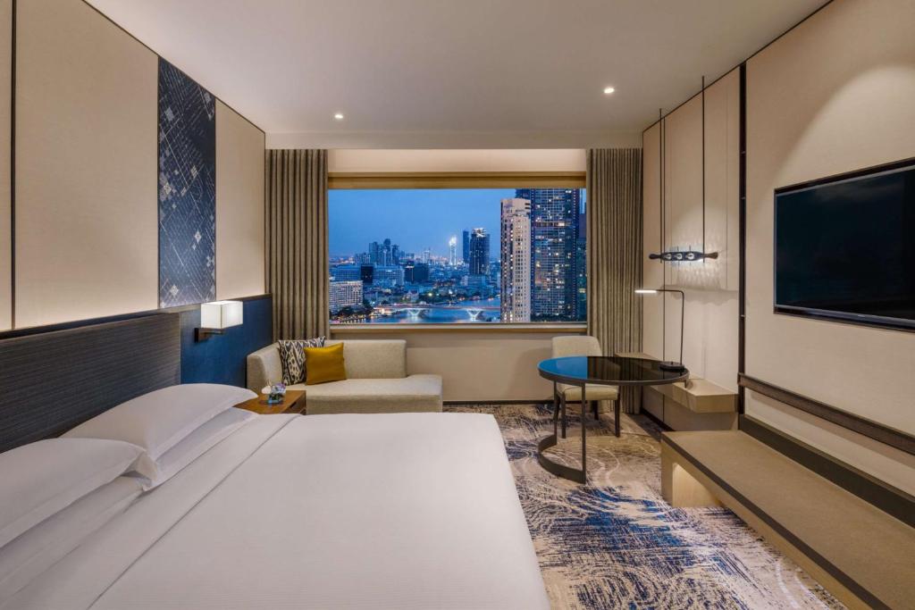 The iconic towers of the Millennium Hilton Bangkok on the riverfront, with the hotel's complimentary shuttle boat sailing on the Chao Phraya River.