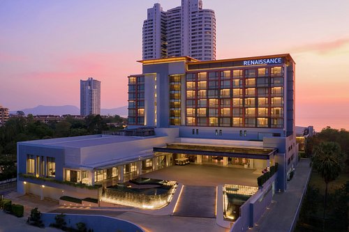 The modern exterior of the Renaissance Pattaya Resort & Spa illuminated against a beautiful sunset sky over the Gulf of Thailand.