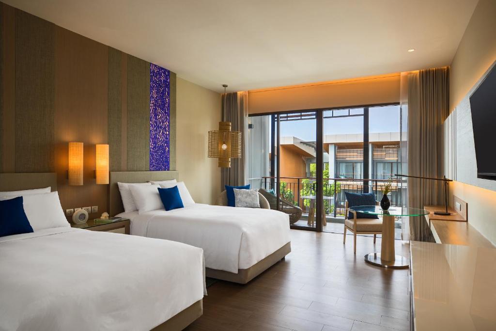 A contemporary twin guest room at the Renaissance Pattaya Resort, featuring clean design, blue accents, and a private balcony.