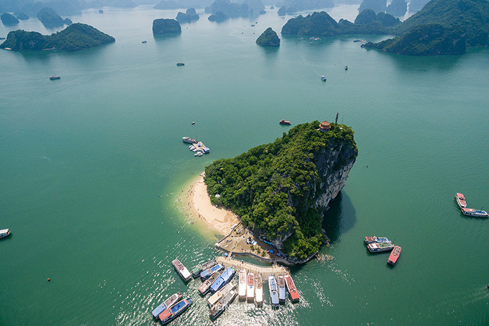 [An aerial perspective of Titop Island, showing the verdant landscape and surrounding emerald sea.]