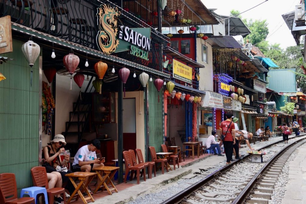 [Vibrant cafes line the narrow tracks of Hanoi's Train Street, an iconic activity covered in this Vietnam travel guide.]