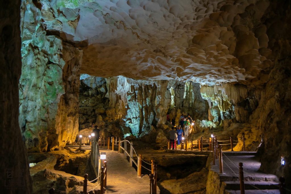 [Impressive stalactites illuminated with golden light inside Sung Sot Cave, one of the amazing things to do in Ha Long Bay.]