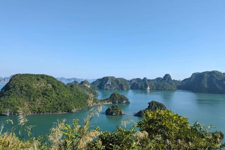 [Tourists kayaking through the arch of Luon Cave, one of the most popular things to do in Ha Long Bay.]