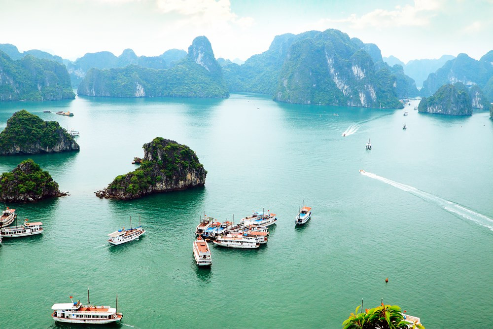 [An aerial perspective of the magnificent limestone karsts rising from the sea in Ha Long Bay, a must-see natural wonder.]