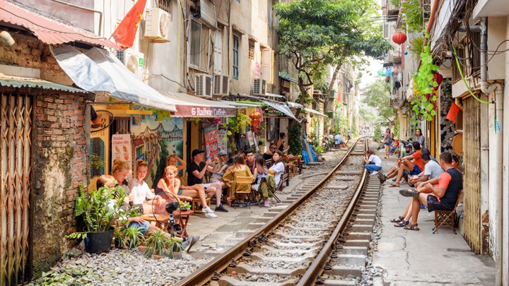 [Travelers enjoying the unique atmosphere of a cafe directly on the railway tracks in Hanoi.]