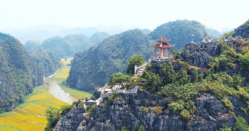 [Travelers making the rewarding climb up the stone steps to the top of Mua Cave, one of the essential things to do in Ninh Binh.]