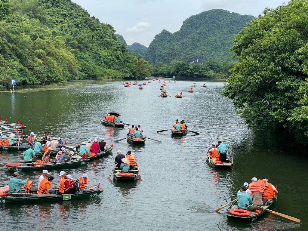 [Travelers enjoying a scenic boat tour through the majestic landscape of Trang An, an essential experience in Northern Vietnam.]