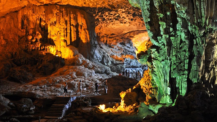 [Visitors exploring the immense and beautifully lit main chamber of Sung Sot Cave.]